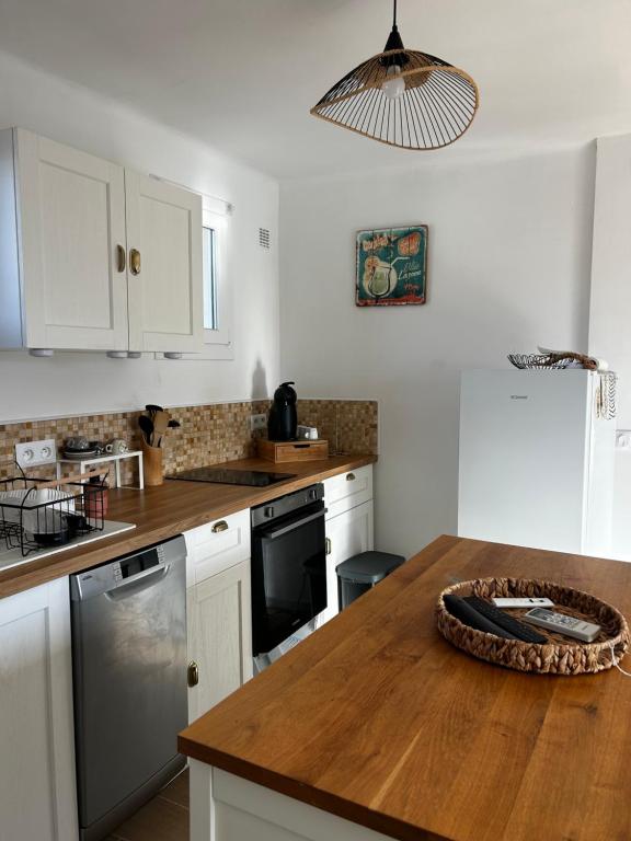 a kitchen with white cabinets and a wooden counter top at Appartement T2 - proche mer - balcon ensoleillé in Six-Fours-les-Plages