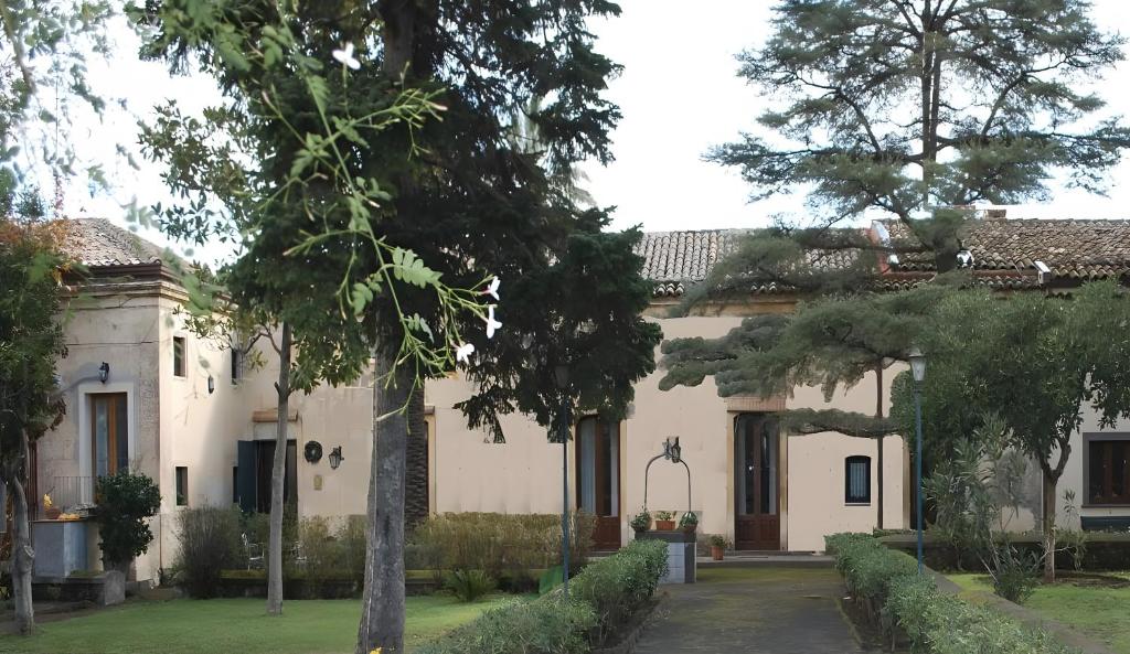 a large white house with trees in the yard at Case Zuccaro in Trecastagni