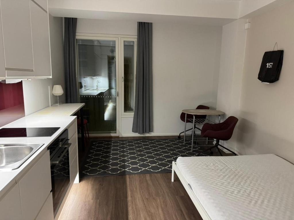 una pequeña cocina blanca con fregadero y mesa en Modern Studio Apt in Design District, en Helsinki