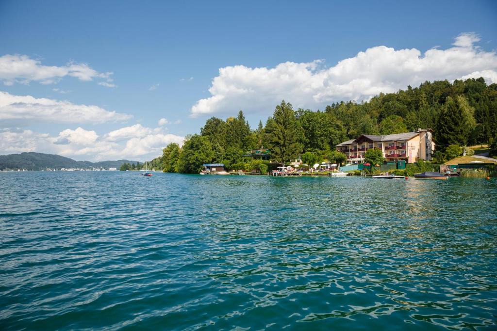 uma vista para um lago com casas e árvores em Seehotel Vinzenz em Velden am Wörthersee