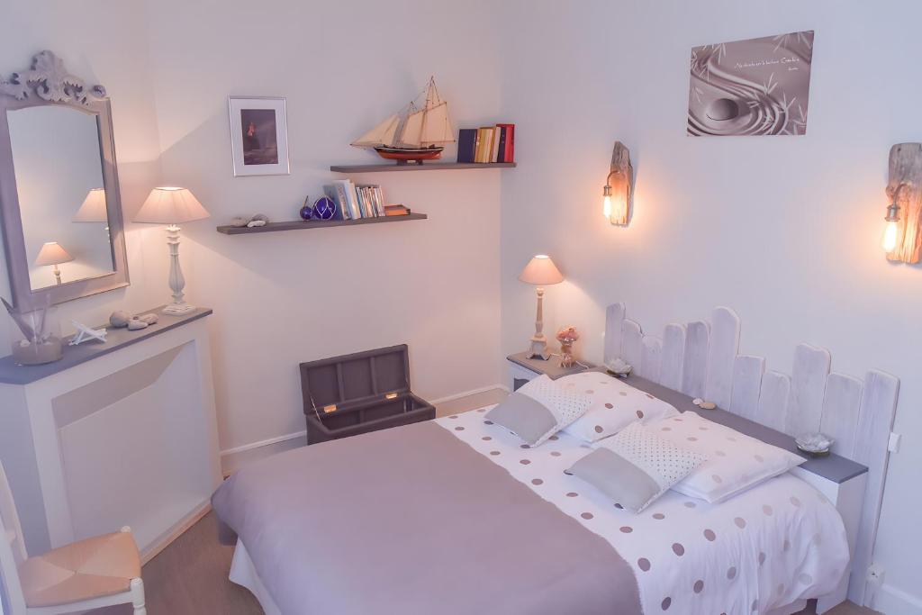 une chambre blanche avec un lit et un miroir dans l'établissement Gîte De La Voûte, à Fécamp