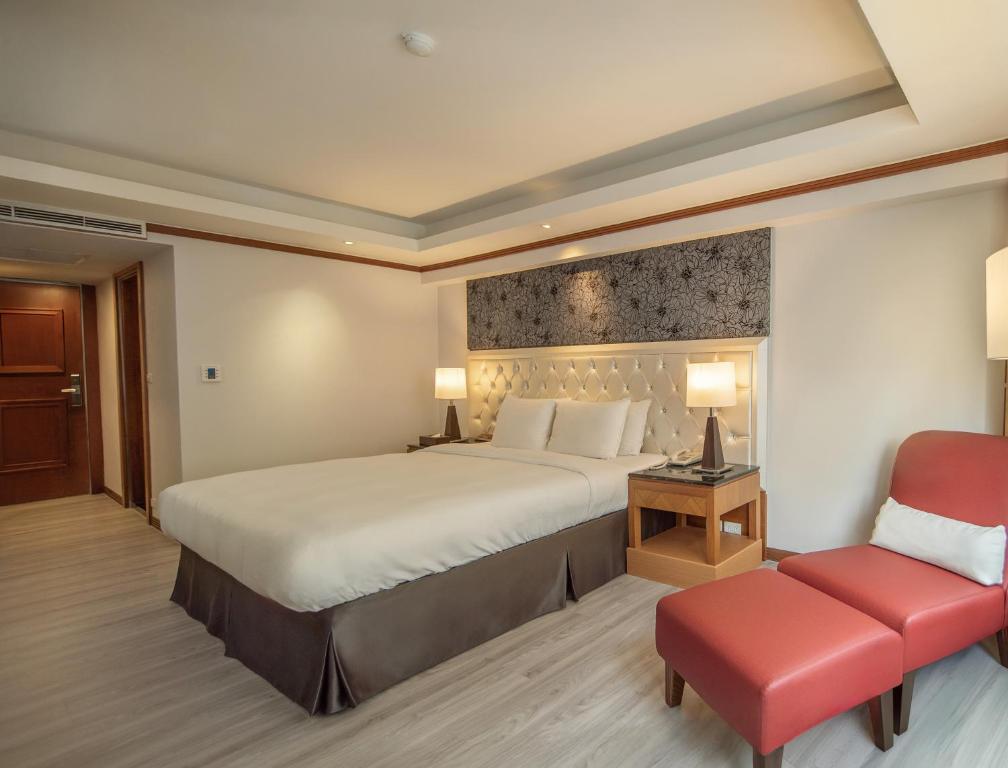 a bedroom with a large bed and a red chair at Hotel Dion in Taichung