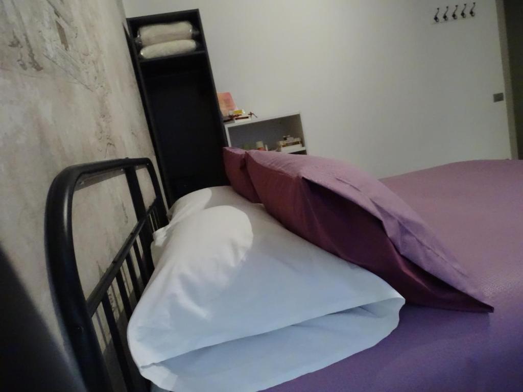 a bed with purple and white sheets and pillows at Cà del corso in Domodossola