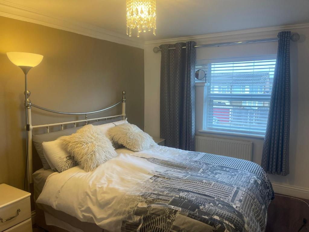 Un dormitorio con una cama con almohadas y una ventana. en Cassandra Homes, en Nevendon