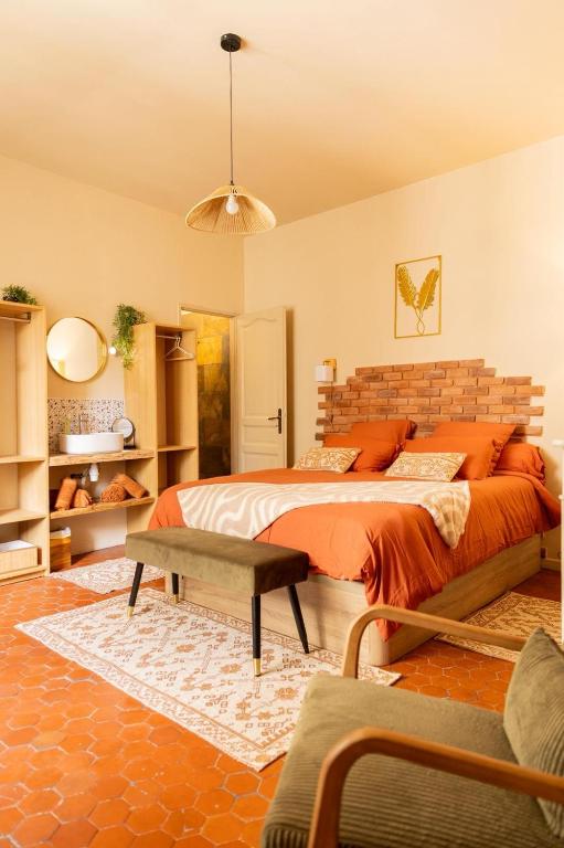 a bedroom with a large bed with an orange blanket at Cosy Cloître, appartement authentique centre Arles in Arles