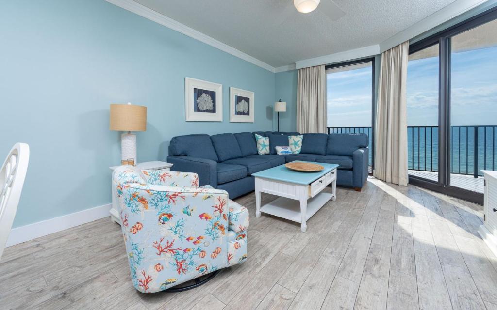 un salon avec un canapé bleu et une table dans l'établissement Phoenix X 711 condo, à Orange Beach