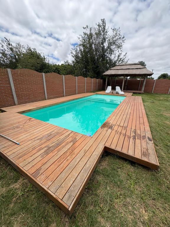 a swimming pool with a wooden deck and a gazebo at hospedaje la familia in Villa Lía