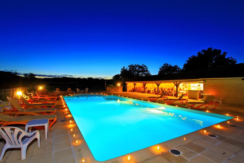 a swimming pool at night with chairs and lights at Gîte Charly in Salignac Eyvigues