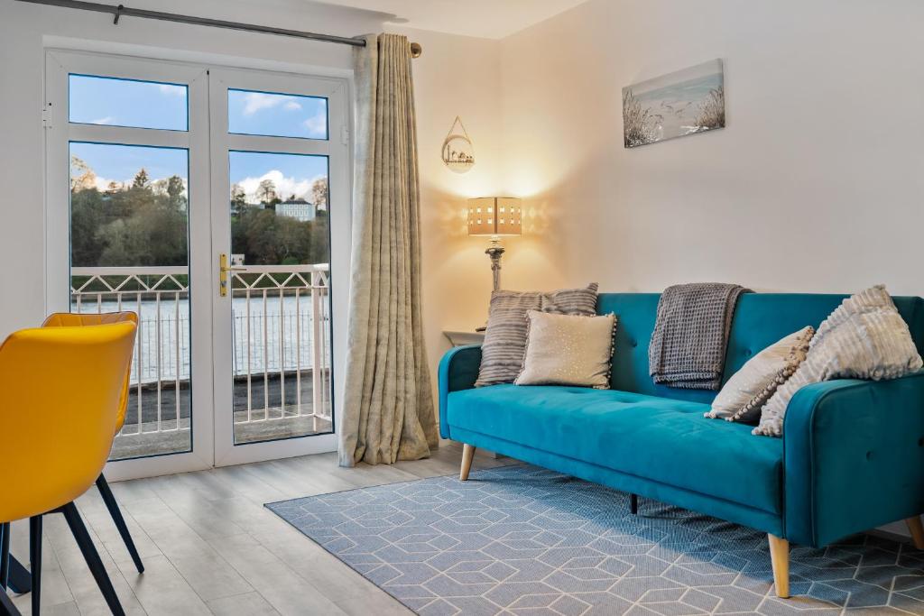 uma sala de estar com um sofá azul e uma varanda em 2 Rushbrooke Hotel Apartments Cobh County Cork em Cobh