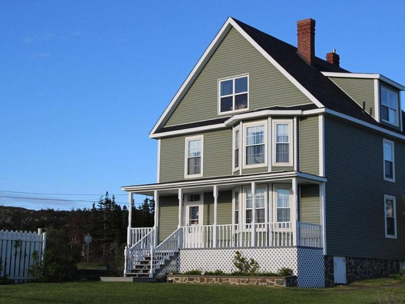 a large green house with a porch and a white fence at Applewood Inn Bed and Breakfast in Twillingate