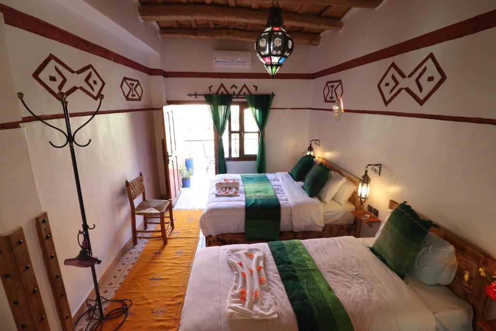 a bedroom with two beds and a lamp at Maison d'Hôte Argana in Aït Idaïr