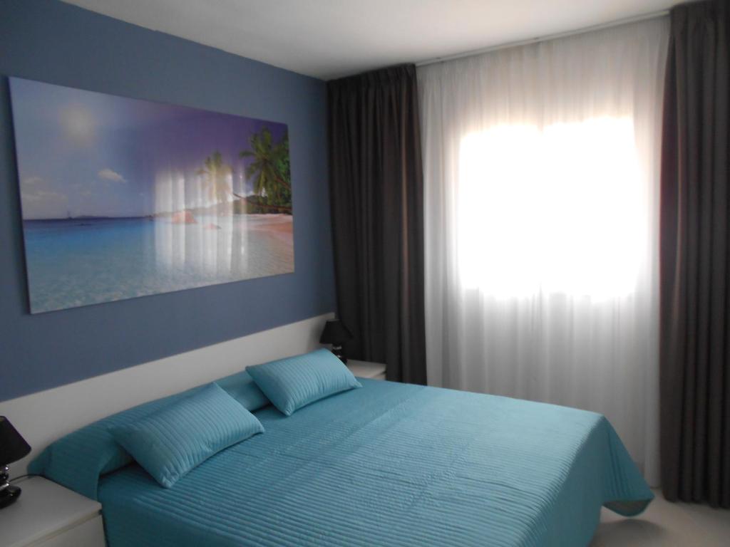 Un dormitorio con una cama azul y una ventana en Orlando Apart, en Adeje