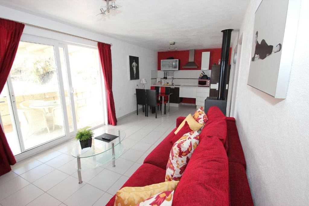 a person laying on a red couch in a living room at Casa Romeo Mit Kaminofen Und Sonnenterrasse in Guía de Isora
