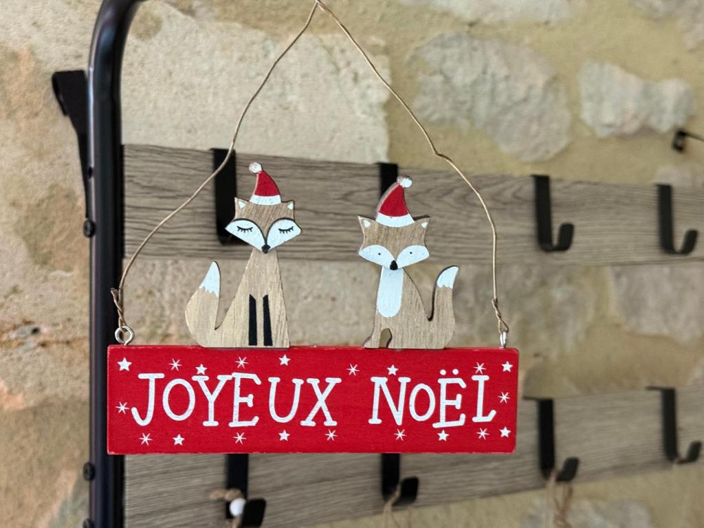 un panneau rouge avec des chats portant des bonnets de Père Noël sur un mur dans l'établissement Pierres d'Estuaire, à Valeyrac