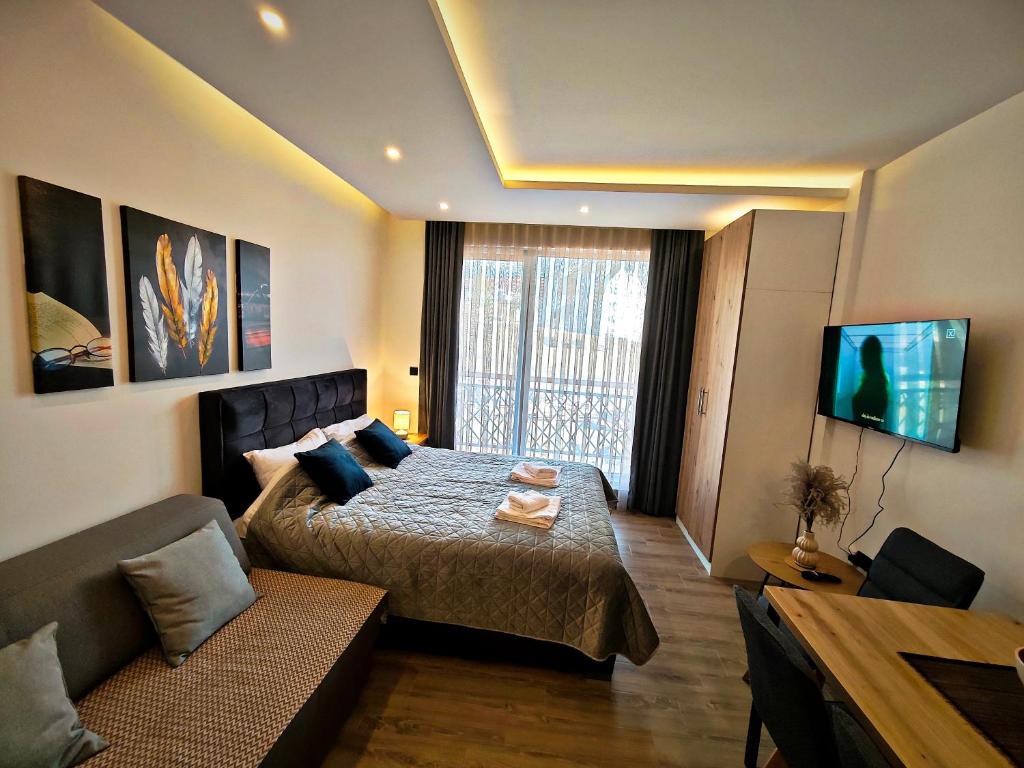 a bedroom with a bed and a couch and a television at Harmony, Residence Hill A85 in Kopaonik