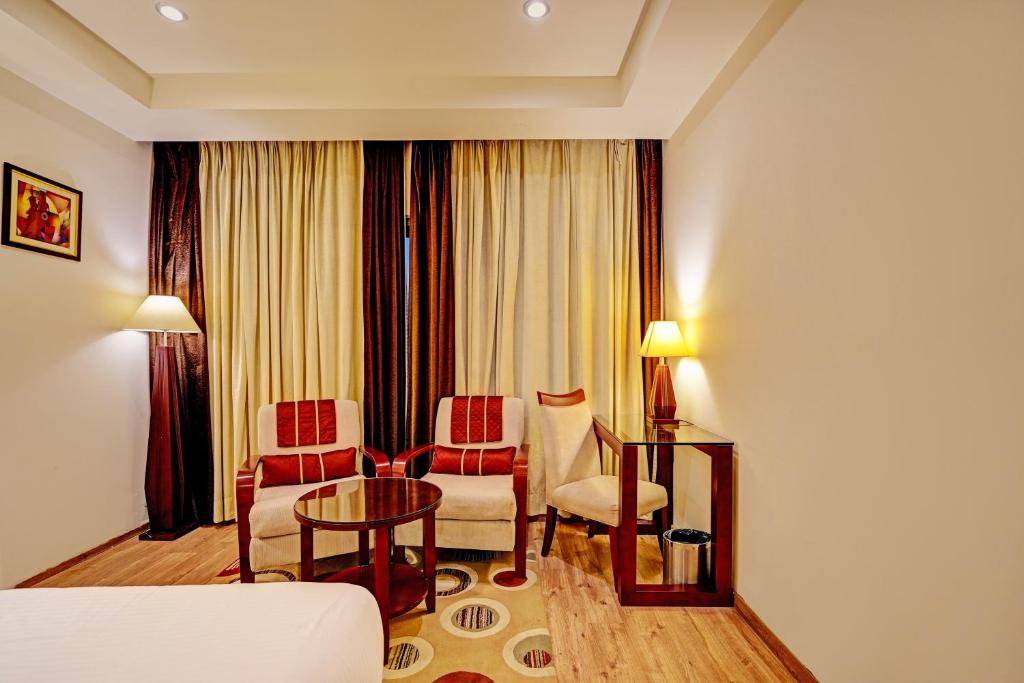 a hotel room with a couch and a table and chairs at Super Townhouse OAK Hotel City Mark Gurgaon in Gurgaon