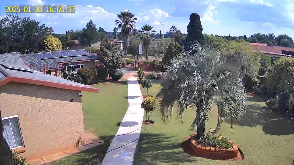 Casablanca Guesthouse في Carletonville: منظر جوي لساحة بها أشجار نخيل ومنزل