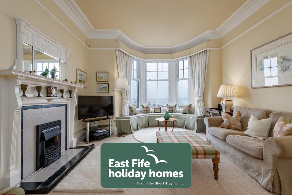 a living room with a fireplace and a tv at Ampersand in Earlsferry