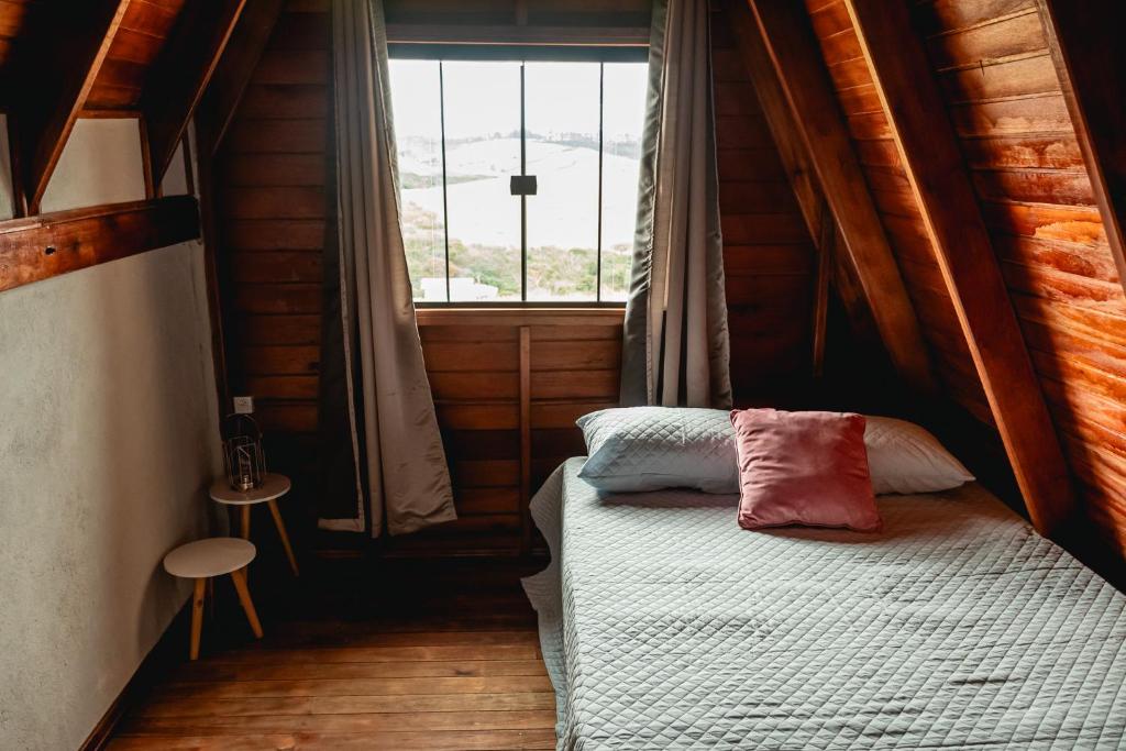 een kleine slaapkamer met een bed en een raam bij Chalé Tia Barbara in Itutinga