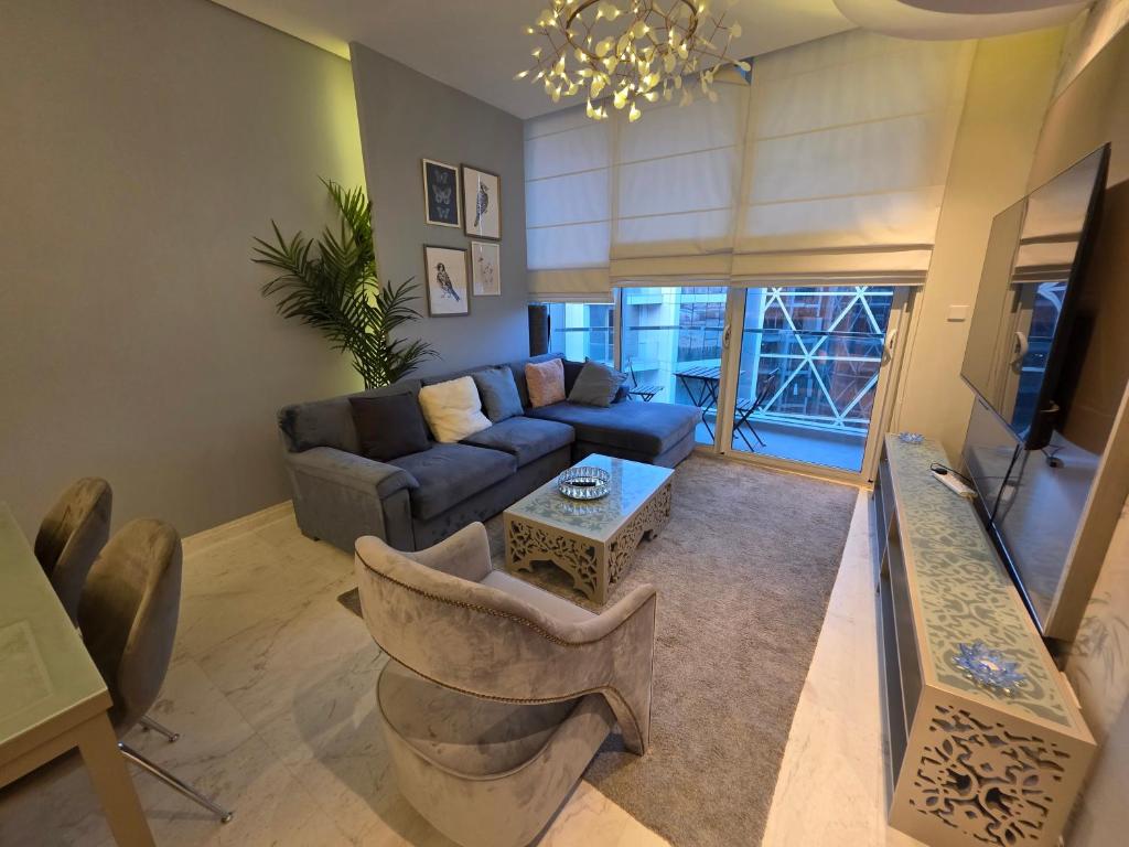 a living room with a blue couch and chairs at Elite 1BR - Sea View & Four Seasons Scene in Manama