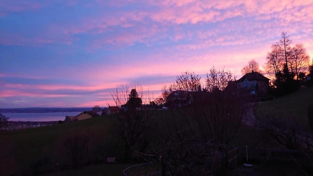 una puesta de sol sobre el agua con una casa en una colina en Ferien In Der Vogelherd, en Wolfhalden 