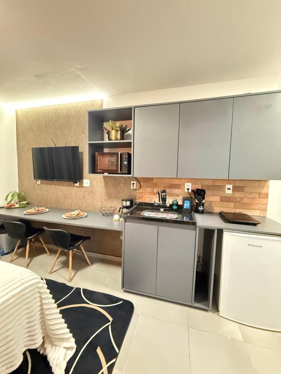 eine Küche mit weißen Schränken und einem Tisch mit Stühlen in der Unterkunft Studio America Gardens in Rio de Janeiro