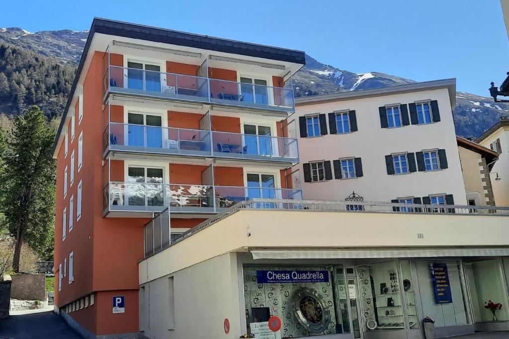 - un grand bâtiment avec des balcons bleus au-dessus dans l'établissement Chesa Quadrella, à Pontresina