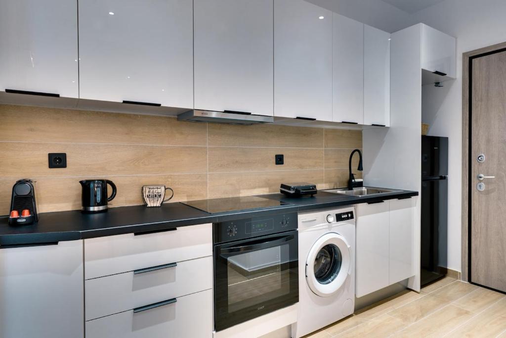 une cuisine avec des armoires blanches et une laveuse et une sécheuse dans l'établissement CityLife studio 2'from metaxourgio station 2A, à Mesochórion