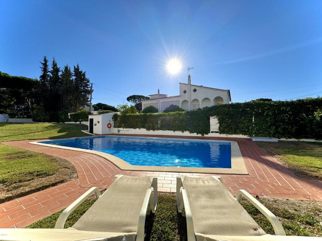 a swimming pool with two lounge chairs in front of a house at Vilamoura Brightness Apartment with Pool by Homing in Vilamoura