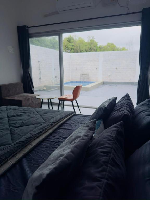a bedroom with a bed and a large window at Casa Oceanus - Pool View Room - Ganpatipule in Nevra