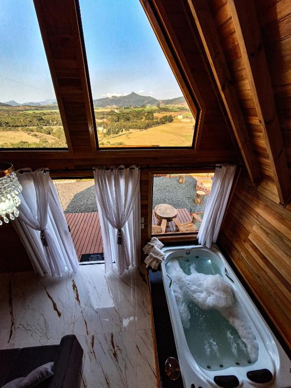 a bathroom with a tub in a room with a window at Cabanas Céu e Mel - Cabana 01 in Bom Retiro