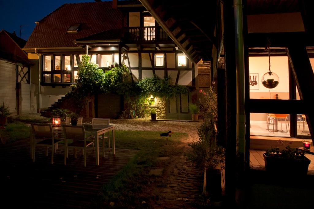 una casa con mesa y sillas en el patio por la noche en B&B Le Lodge en Bourgheim