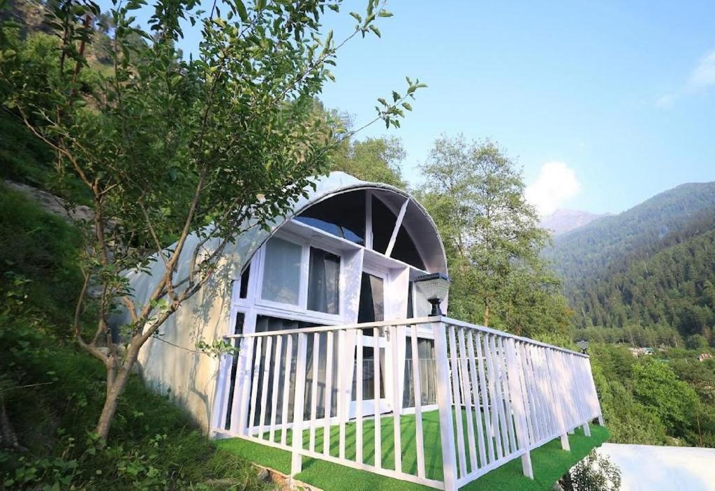 Una casa redonda con un porche blanco en el bosque. en The Lush Pods, en Jāmb