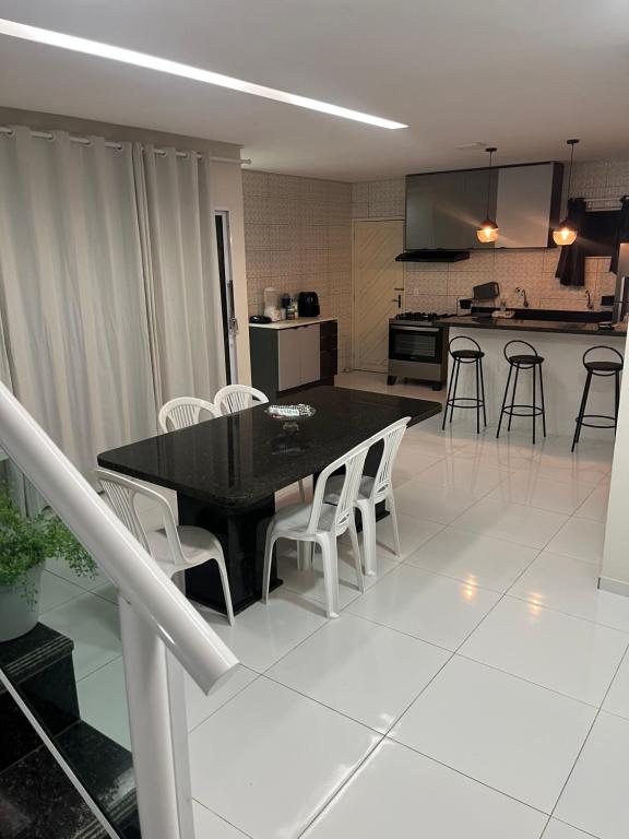 eine Küche mit einem schwarzen Tisch und weißen Stühlen in der Unterkunft ParkMar III - São José, Maragogi in São José da Coroa Grande