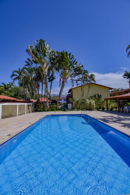 a large swimming pool with palm trees and a building at Casa em condomínio com piscina in Paraty