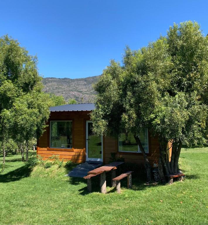 a small cabin in a field with a tree at Prunus Casa de Montaña in El Hoyo