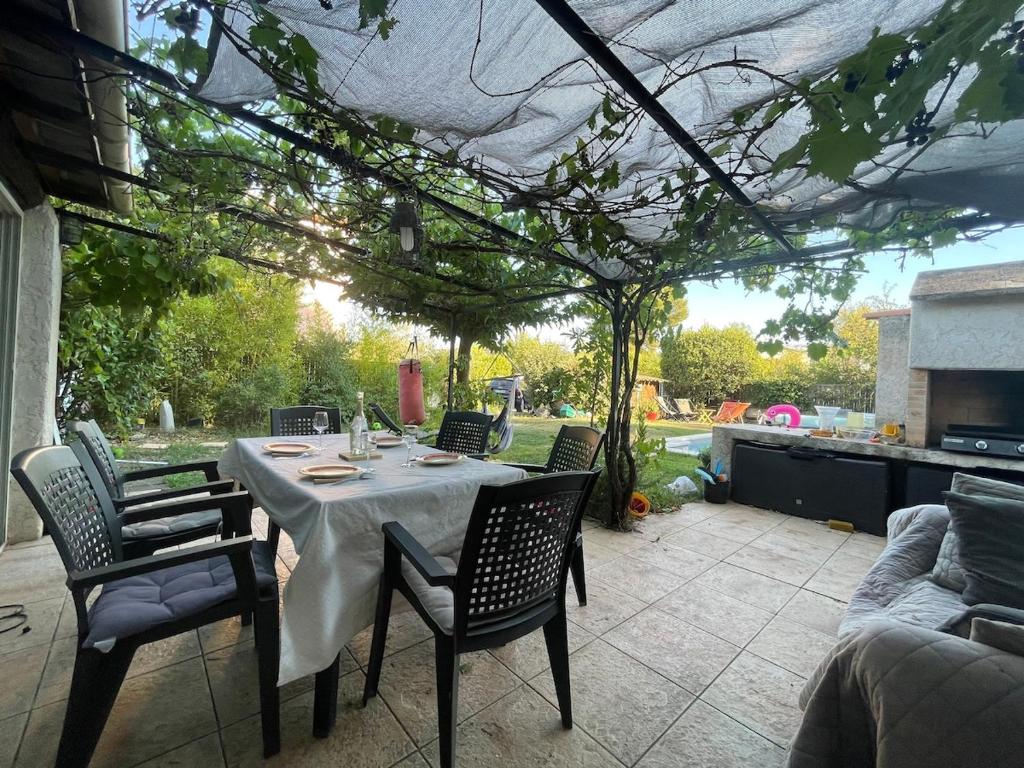 un patio avec une table et des chaises sous une pergola dans l'établissement Studio with pool and quiet, non-shared garden, à Gardanne