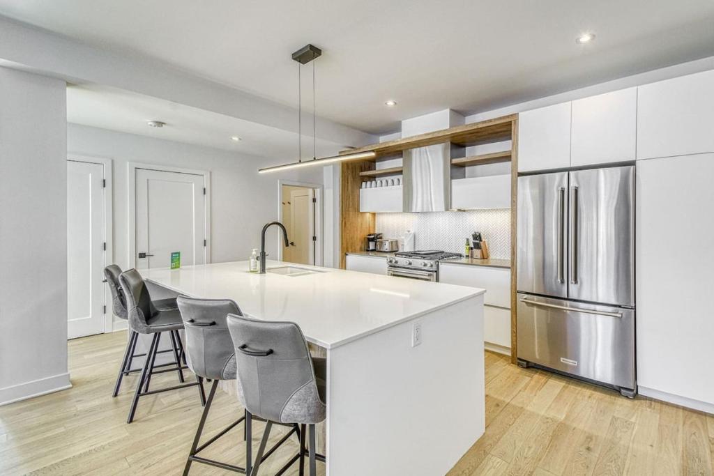 a kitchen with white cabinets and a kitchen island with stools at Verbier Condo in Tremblant with Mountain Views - 105 Verbier in Mont-Tremblant