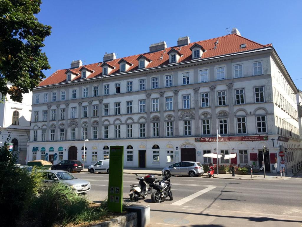 duży biały budynek z czerwonym dachem na ulicy w obiekcie Easy Vienna Apartments w Wiedniu