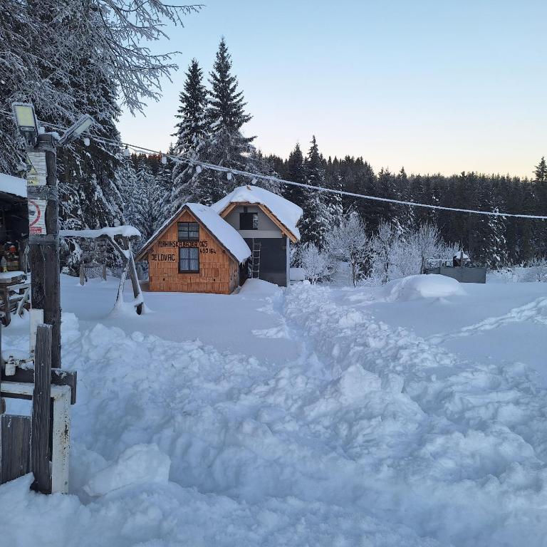 a log cabin in the snow with a pile of snow at Studio apartman Planinska Bajka in Olovo
