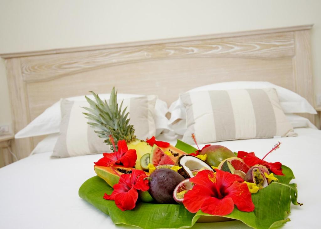 a plate of fruit and flowers on a bed at Brezza Marina Luxury Rooms in Cagliari