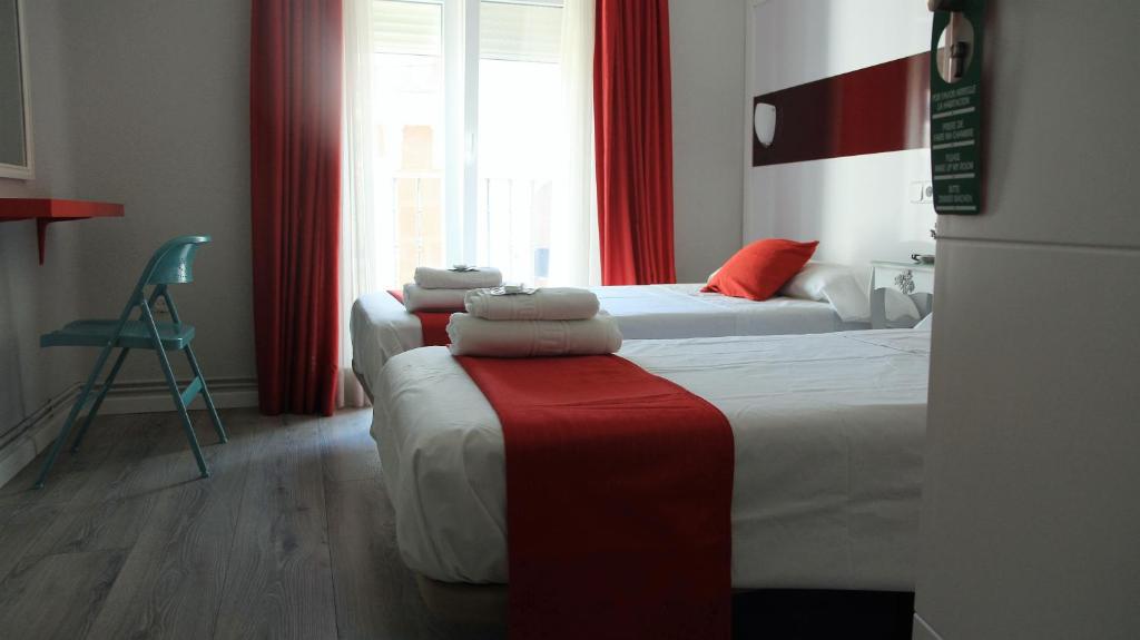 a hotel room with two beds with red curtains at Pension Antonio in Madrid