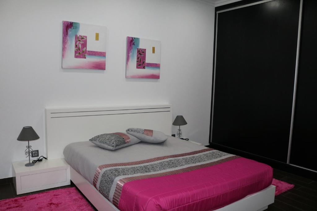 een slaapkamer met een groot bed en een roze deken bij Vivenda Paraíso in Candelária