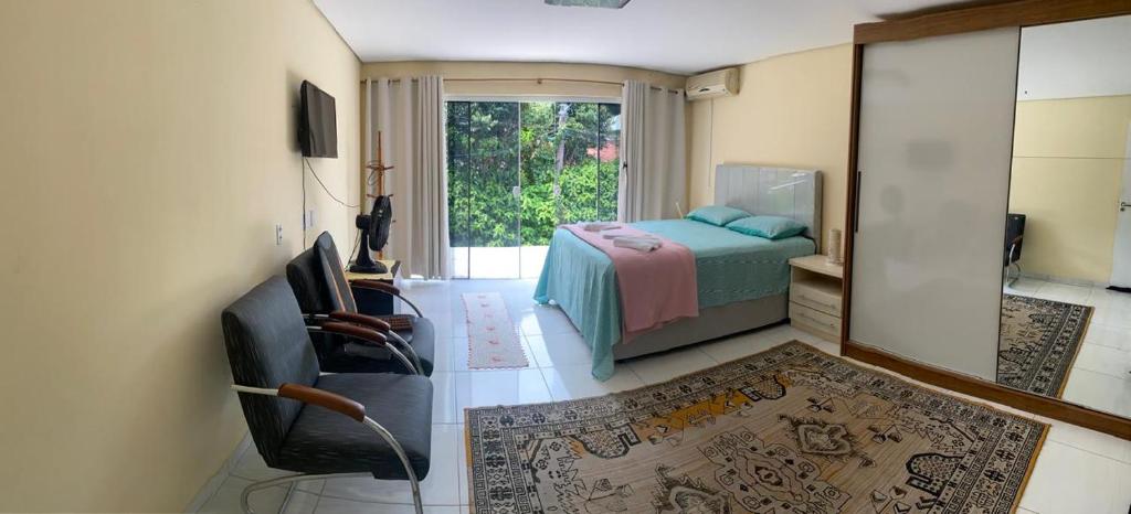 ein Schlafzimmer mit einem Bett, einem Stuhl und einem Fenster in der Unterkunft Encantadora Casa Campeche in Florianópolis