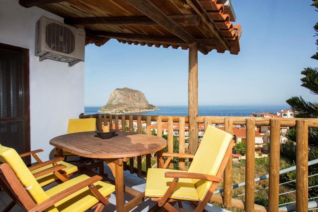 uma mesa e cadeiras numa varanda com o oceano em Monemvasia Green Apartments em Monemvasia