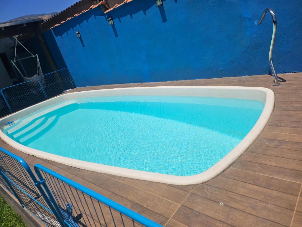 a swimming pool on a deck with a blue wall at Casa praia in Caraguatatuba