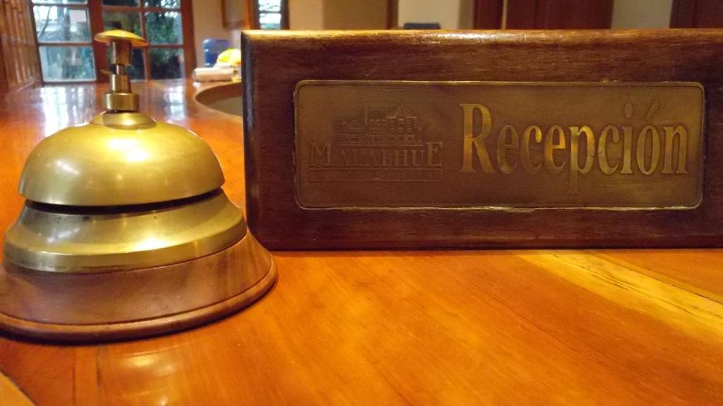 um sinal numa mesa de madeira com um sino em Hotel Malalhue em Pucón