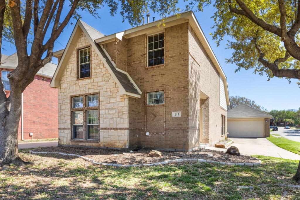 a brick house with a tree in front of it at Fenced Backyard - Workspace - Near DFW Airport in Euless