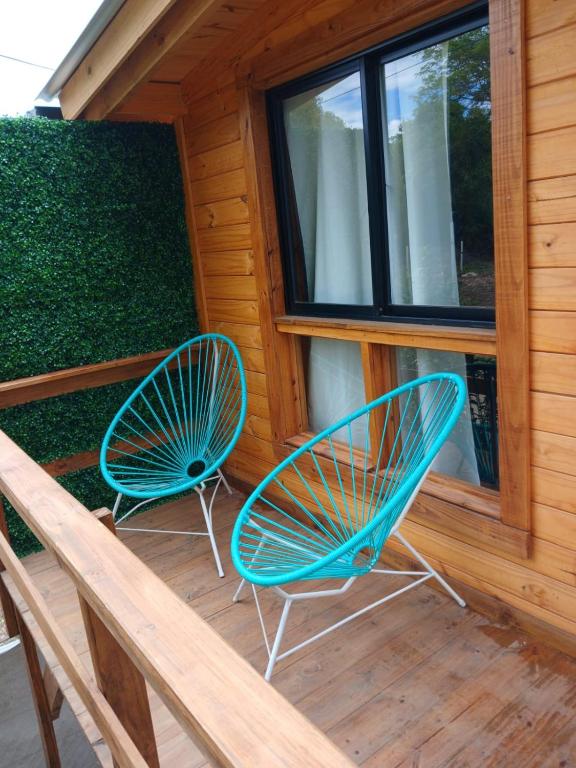 two blue chairs sitting on the porch of a cabin at Depto Cabañero Lumai in Villa Ciudad Parque