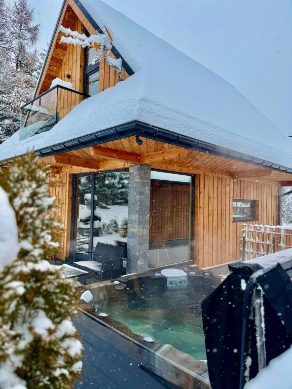 a house covered in snow with a swimming pool at Domki Siodemka 7a prywatne jacuzzi, sauna, 7b prywatne jacuzzi, sauna i klimatyzacja, wyposażenie zależy od wybranego domku in Zakopane